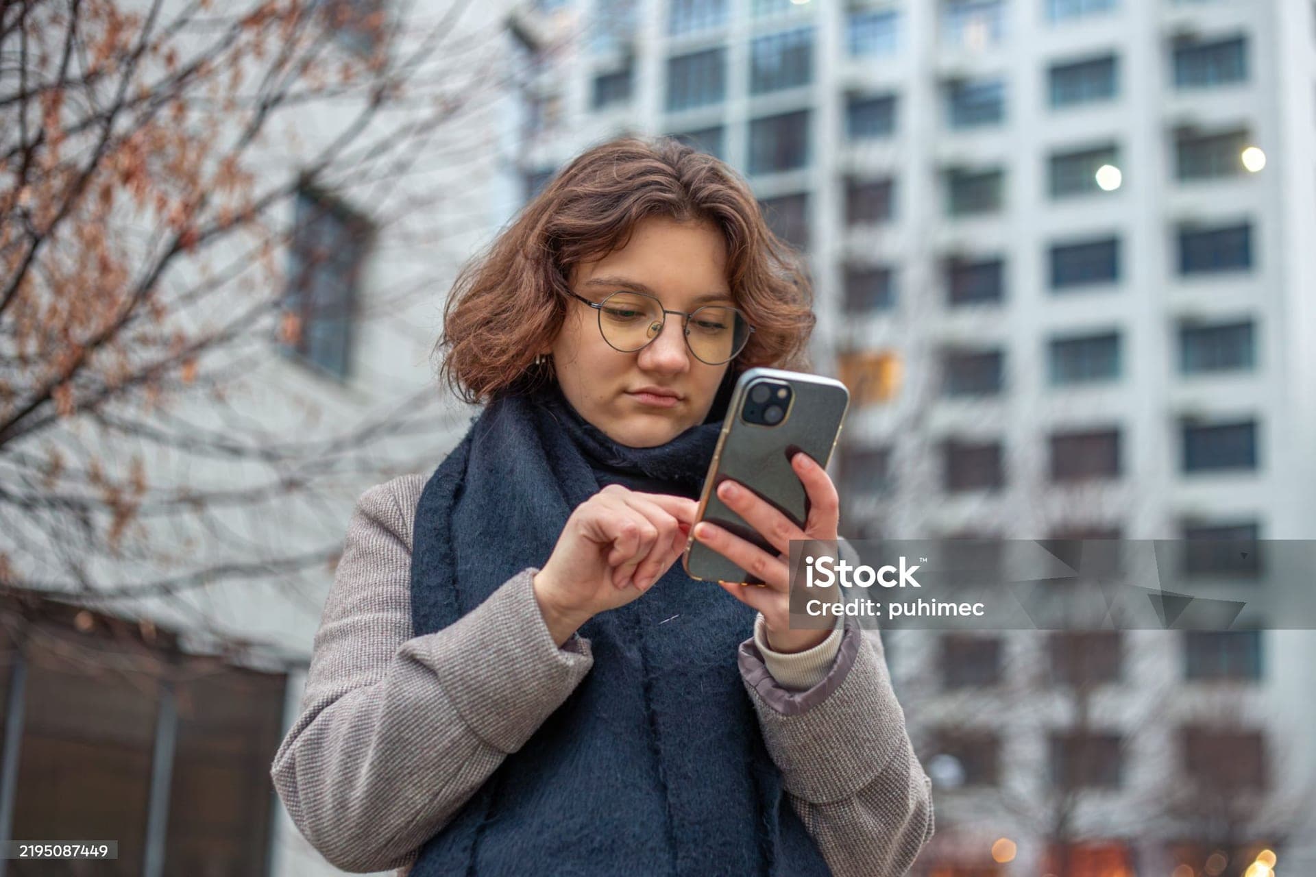 A young woman typing on her phone in the city