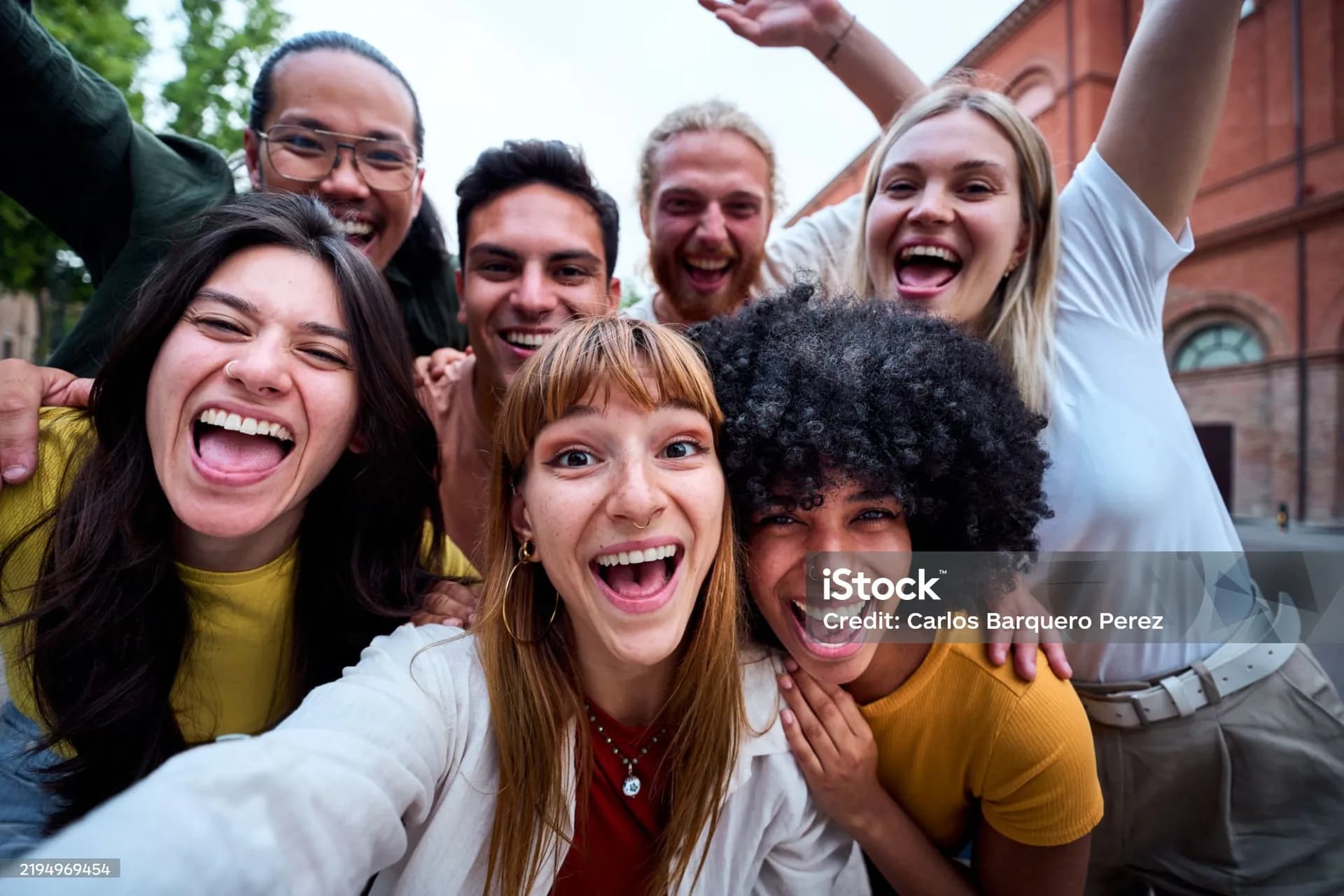A group of young friends outdoors taking a selfie together, laughing.